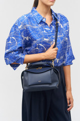 Profile view of model wearing the Oroton Mica Small Bowler in North Sea and Pebble leather for Women
