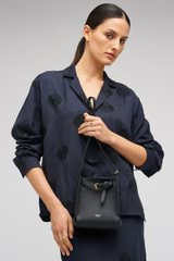 Profile view of model wearing the Oroton Margot Tiny Bucket Bag in Black and Pebble leather for Women