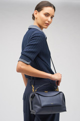 Profile view of model wearing the Oroton Mica Small Bowler in North Sea and Pebble leather for Women