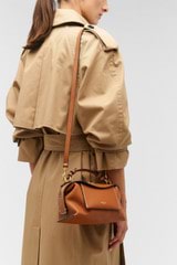 Profile view of model wearing the Oroton Mica Mini Bowler in Brandy and Pebble leather for Women