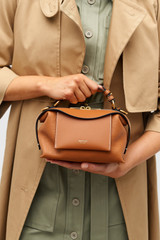 Profile view of model wearing the Oroton Mica Mini Bowler in Brandy and Pebble leather for Women