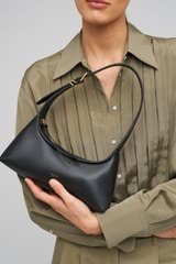 Profile view of model wearing the Oroton Cinder Mini Baguette in Black and Smooth leather for Women
